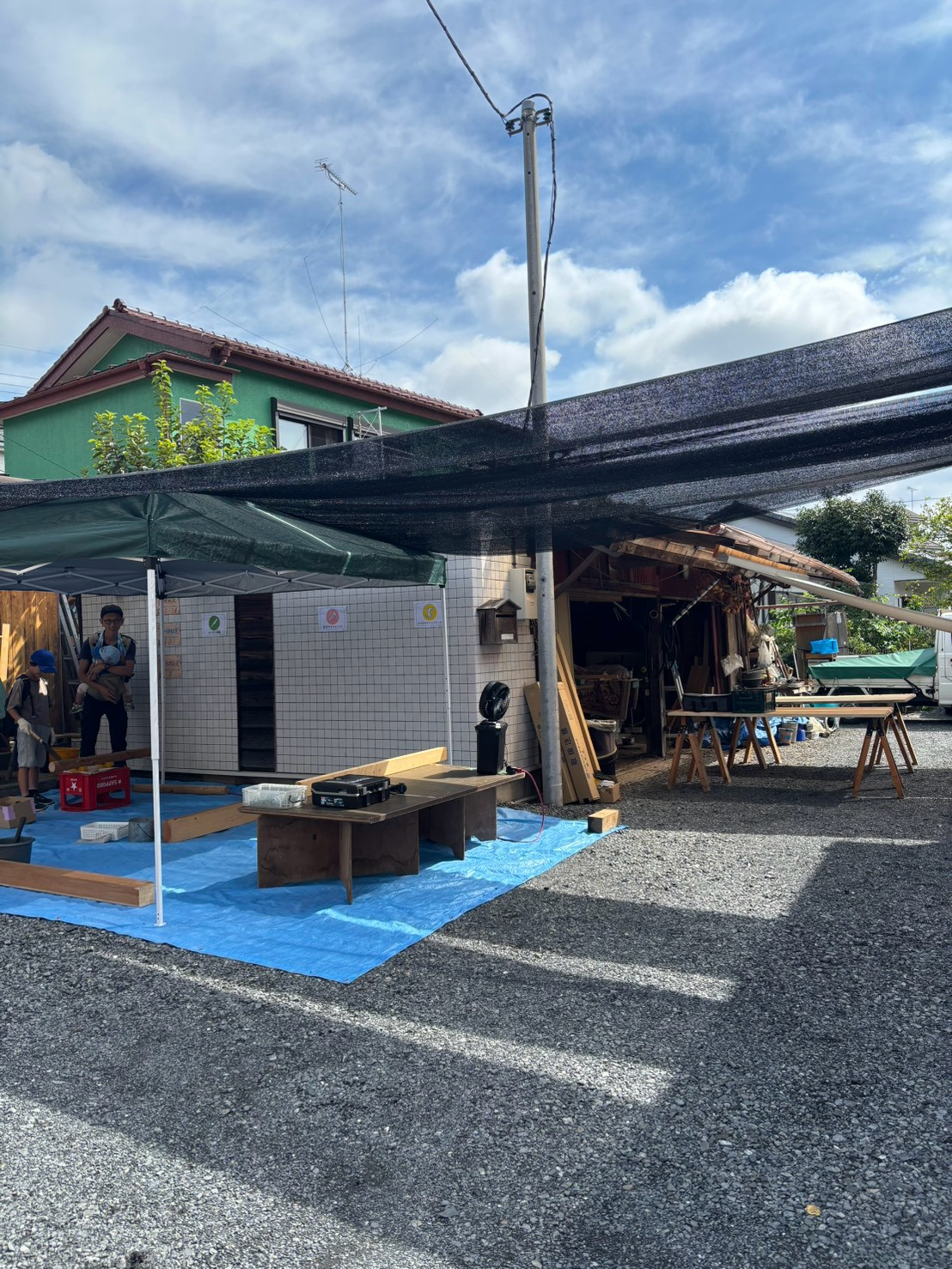 岡部工務店の夏祭りイベント会場。屋外テントの下で大工仕事体験や網戸貼替えサービスを開催