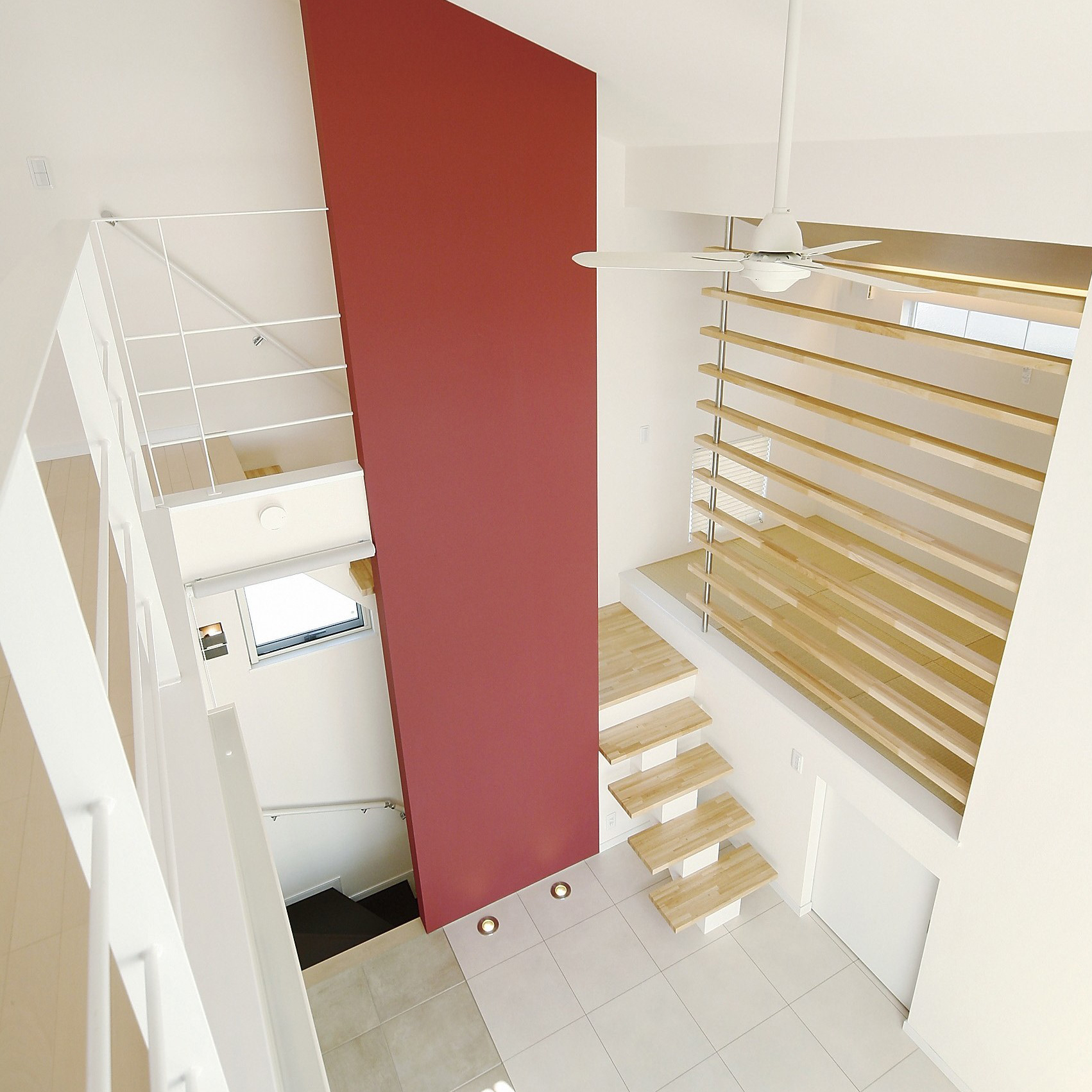 岡部工務店が施工した赤いアクセントウォールが目を引く吹き抜けの施工事例